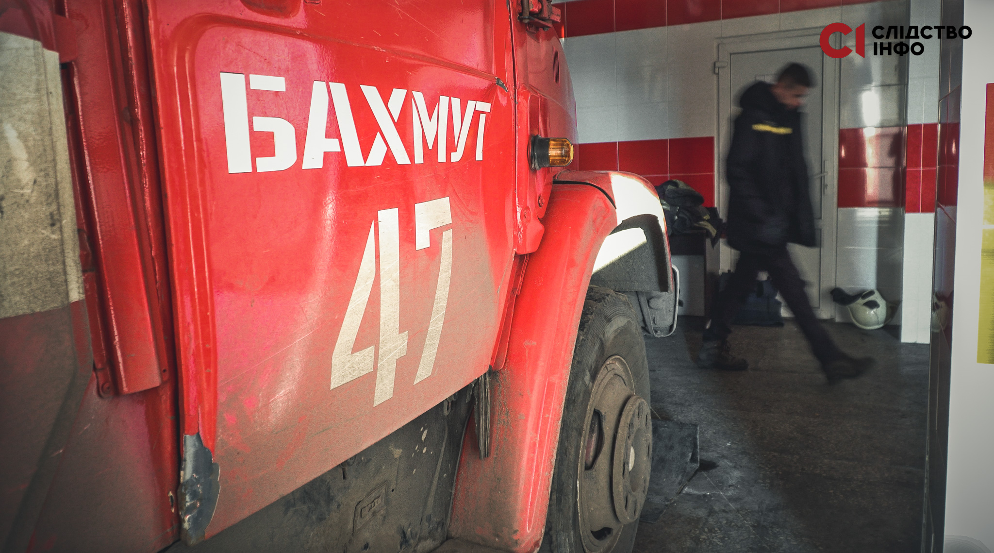 Частина червоної пожежної машини з написом "Бахмут 47", на фоні йде чоловік