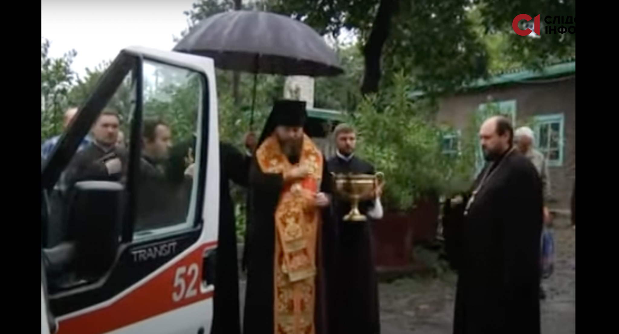 На фото натовп людей, священник РПЦ в Україні освячує машину швидкої допомоги. Над ним тримають чорну парасолю
