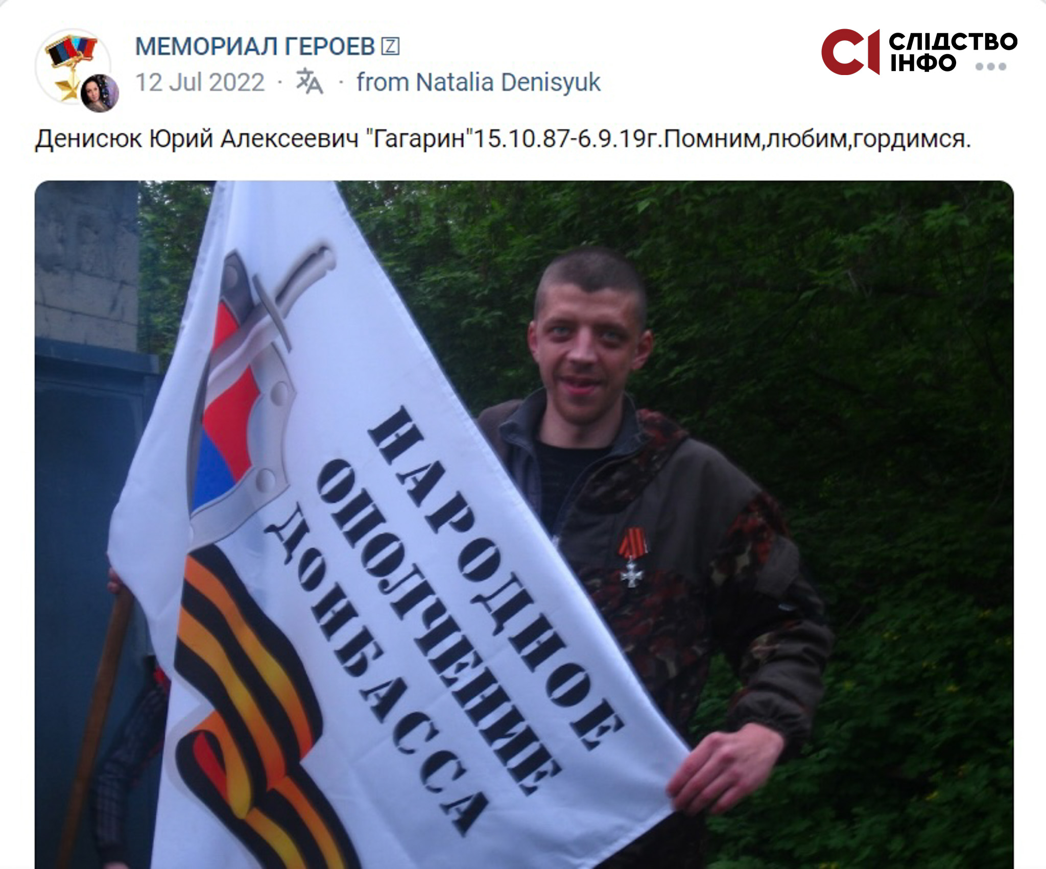 Чоловік стоїть на фоні дерева, у руках тримає білий прапор з написом "Народное ополчение Донбасса" і георгіївською стрічкою