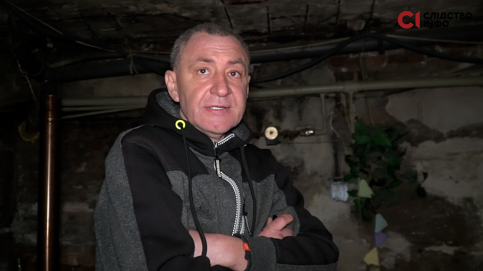 Чоловік зі складеними руками стоїть у підвалі