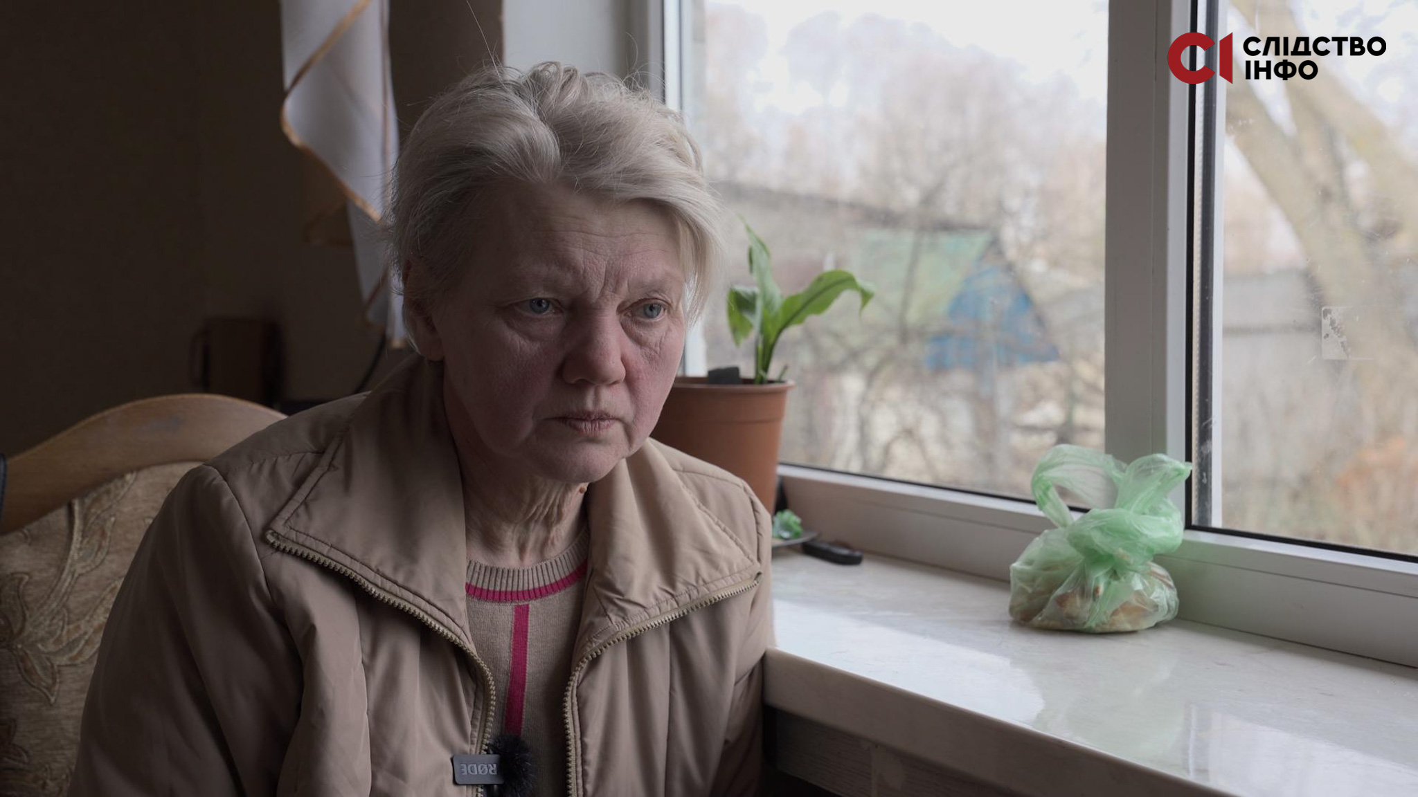 Жінка з білявим волоссям сидить біля вікна